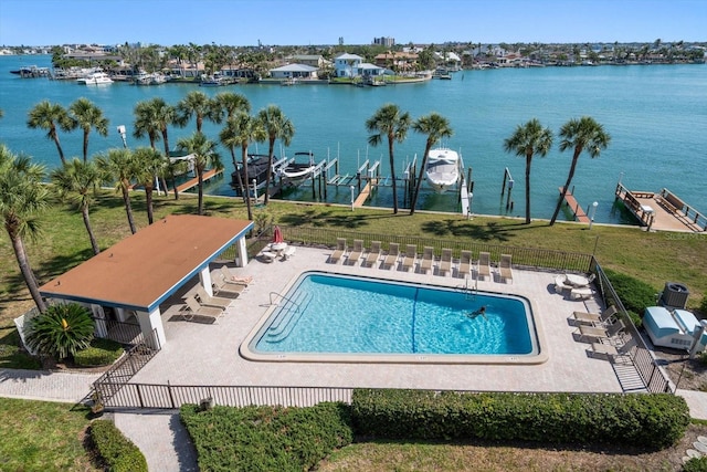 community pool featuring a patio, a water view, fence, and a lawn