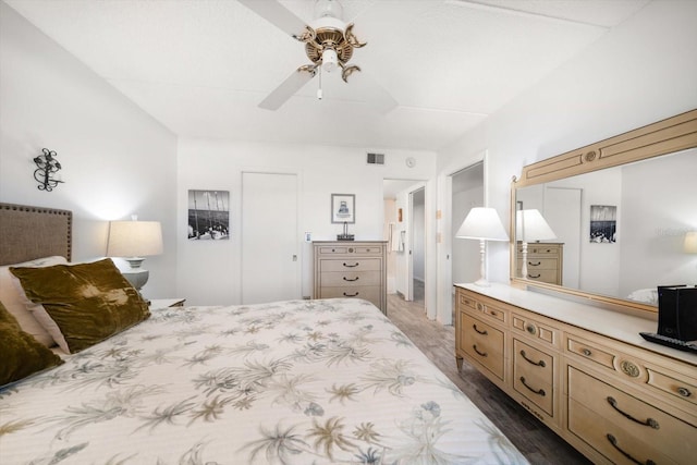 bedroom with ceiling fan, visible vents, and wood finished floors