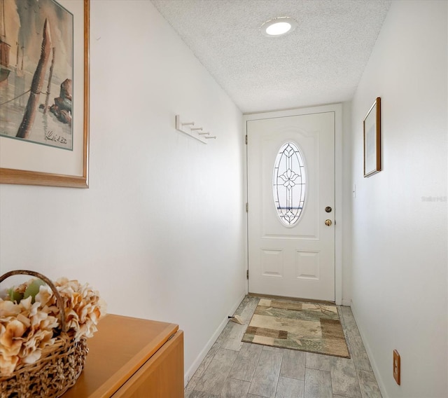 entryway featuring recessed lighting, a textured ceiling, baseboards, and light wood-style floors