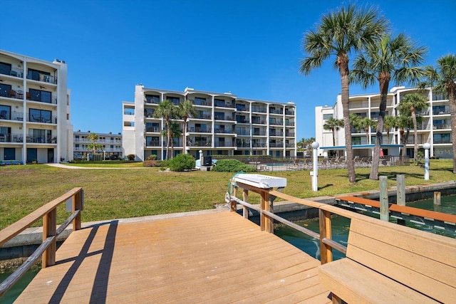 view of dock with a water view and a lawn