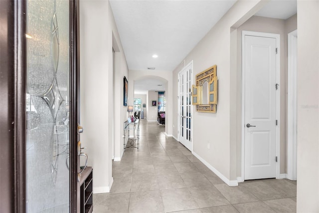 11606 Kilkenny Coral Dr, Riverview, FL 33579 - hallway with arched walkways, light tile patterned floors, baseboards, french doors, and recessed lighting