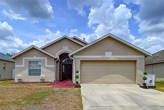 24305 Denali Ct, Lutz, FL 33559 - view of front of home with brick siding, concrete driveway, a garage, and stucco siding