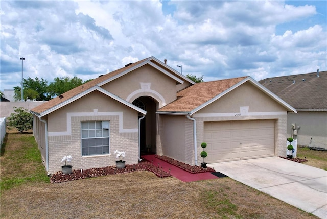 24305 Denali Ct, Lutz, FL 33559 - view of front of property with an attached garage, stucco siding, concrete driveway, brick siding, and roof with shingles