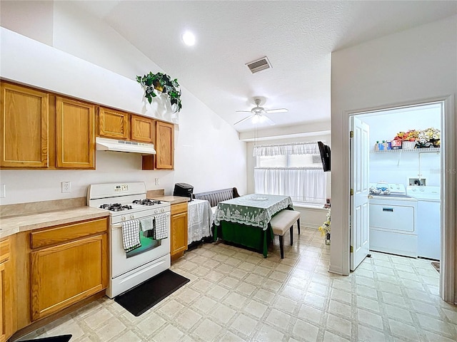 24305 Denali Ct, Lutz, FL 33559 - kitchen with white gas range, washing machine and clothes dryer, under cabinet range hood, vaulted ceiling, and ceiling fan