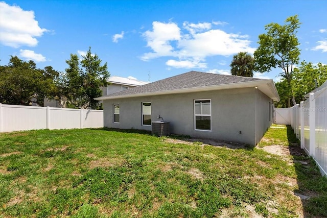 2906 E Columbus Dr, Tampa, FL 33605 - back of house featuring a yard, stucco siding, central AC unit, roof with shingles, and a fenced backyard