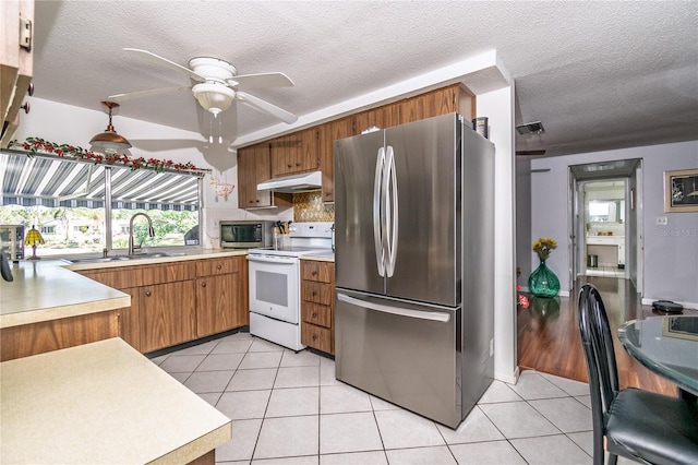 12303 Fieldstone Ln, Hudson, FL 34667 - kitchen with stainless steel appliances, a sink, under cabinet range hood, light tile patterned flooring, and a textured ceiling