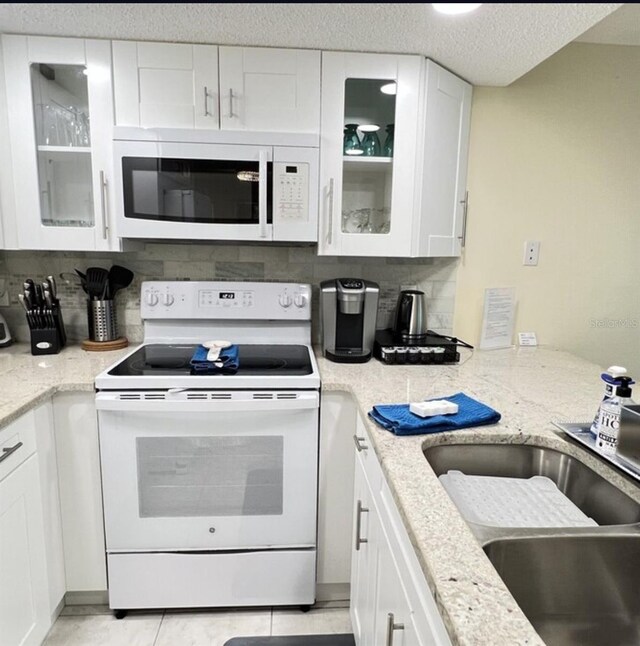 323 Rex Pl Unit G, Madeira Beach, FL 33708 - kitchen with white appliances, decorative backsplash, white cabinets, and a textured ceiling
