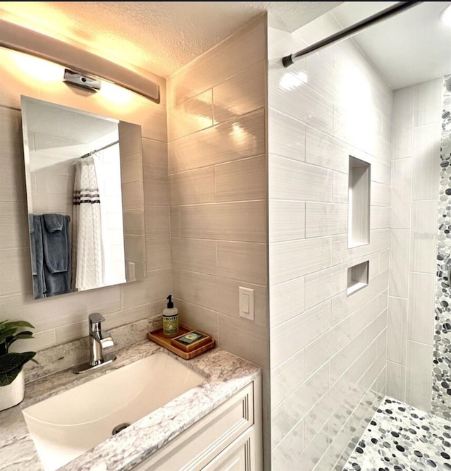 323 Rex Pl Unit G, Madeira Beach, FL 33708 - full bathroom featuring vanity, a tile shower, tile walls, and a textured ceiling