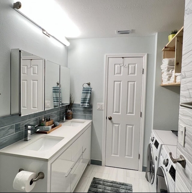 323 Rex Pl Unit G, Madeira Beach, FL 33708 - bathroom with independent washer and dryer, double vanity, decorative backsplash, and a textured ceiling