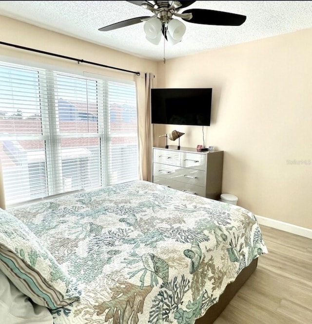 323 Rex Pl Unit G, Madeira Beach, FL 33708 - bedroom featuring wood finished floors, a textured ceiling, and ceiling fan