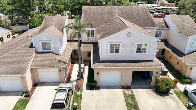 view of property with driveway, stucco siding, roof with shingles, and an attached garage