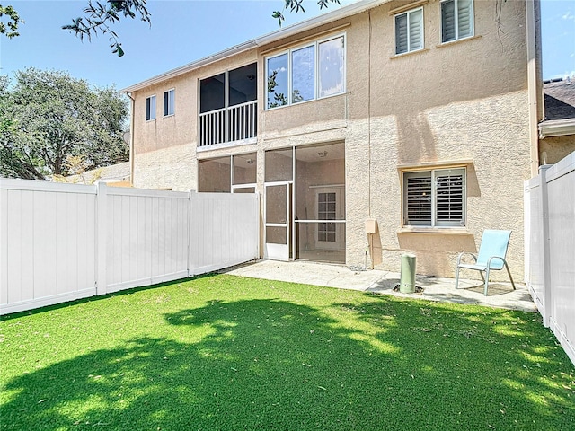 back of house featuring a yard, stucco siding, and a fenced backyard