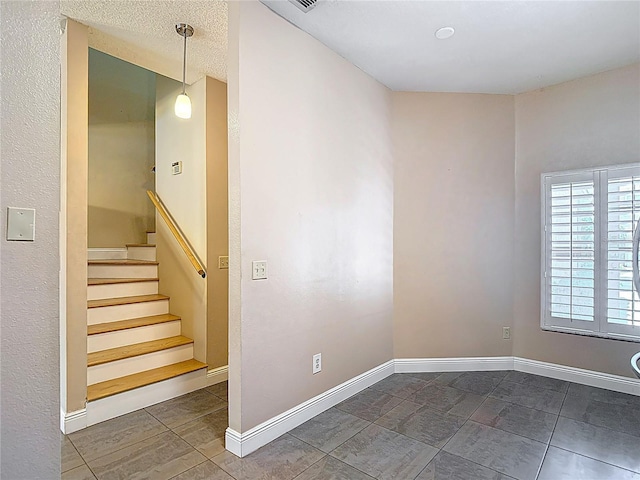 empty room featuring stairway and baseboards