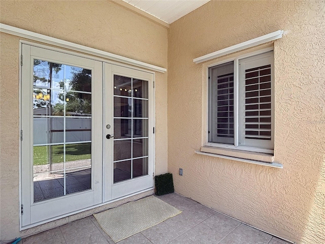 entrance to property with a patio area, stucco siding, and french doors