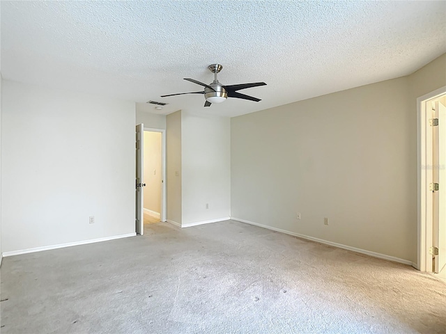 carpeted spare room with baseboards, ceiling fan, visible vents, and a textured ceiling