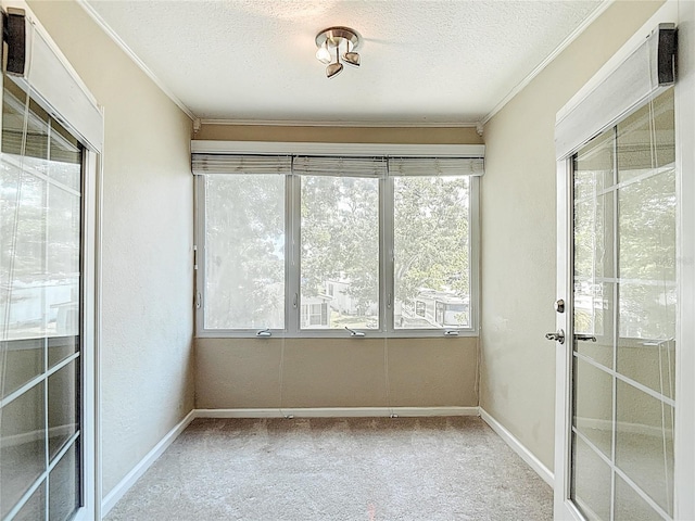 unfurnished sunroom with a textured ceiling, carpet, ornamental molding, and baseboards