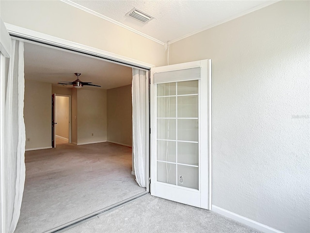 empty room with visible vents, crown molding, ceiling fan, carpet flooring, and baseboards