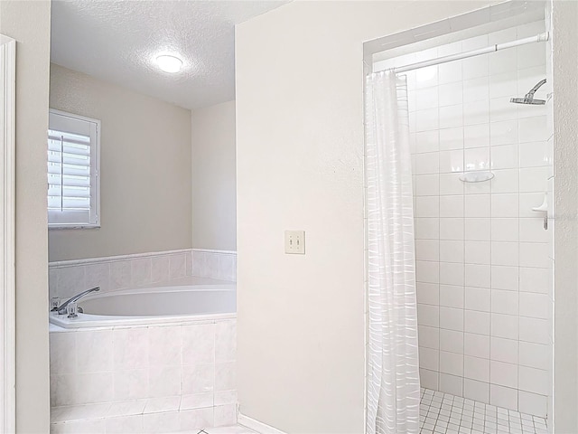 full bathroom featuring a bath, a textured ceiling, and a stall shower