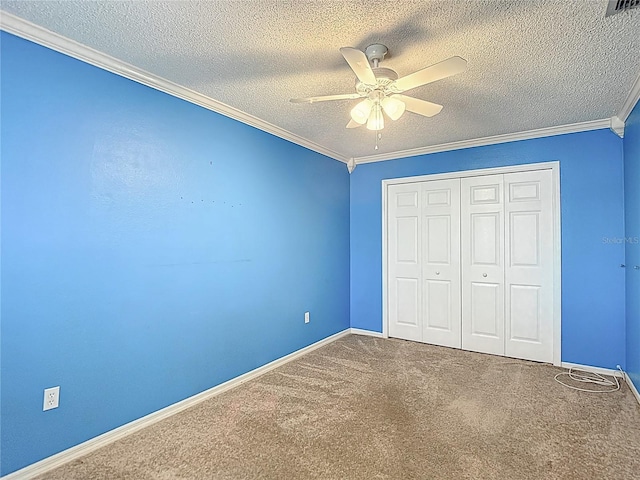 unfurnished bedroom featuring carpet, a textured ceiling, ornamental molding, a closet, and baseboards