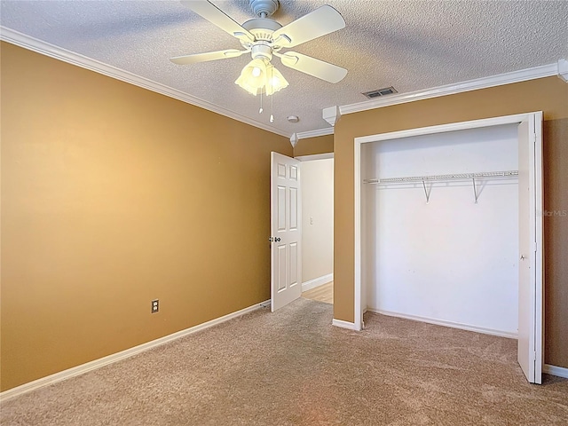 unfurnished bedroom featuring a closet, a textured ceiling, carpet, visible vents, and crown molding