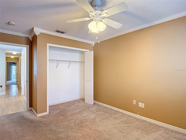 unfurnished bedroom featuring a closet, crown molding, a textured ceiling, visible vents, and light colored carpet