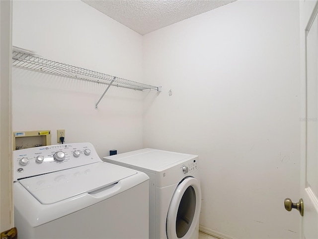 washroom featuring washing machine and clothes dryer, laundry area, and a textured ceiling