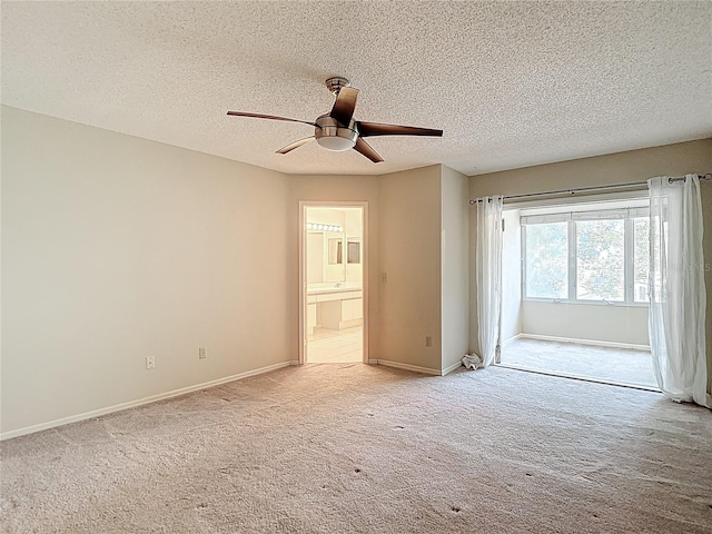spare room featuring ceiling fan, light carpet, baseboards, and a textured ceiling