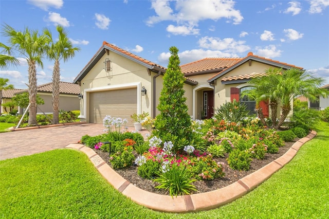 mediterranean / spanish home featuring stucco siding, a front yard, a tiled roof, and driveway