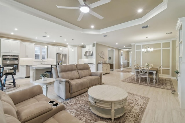living room featuring a chandelier, ceiling fan, recessed lighting, a raised ceiling, and crown molding