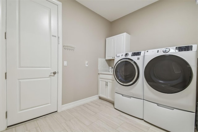 washroom with washer and clothes dryer, cabinet space, and baseboards