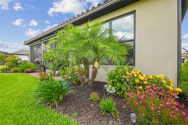 view of side of home with stucco siding and a lawn