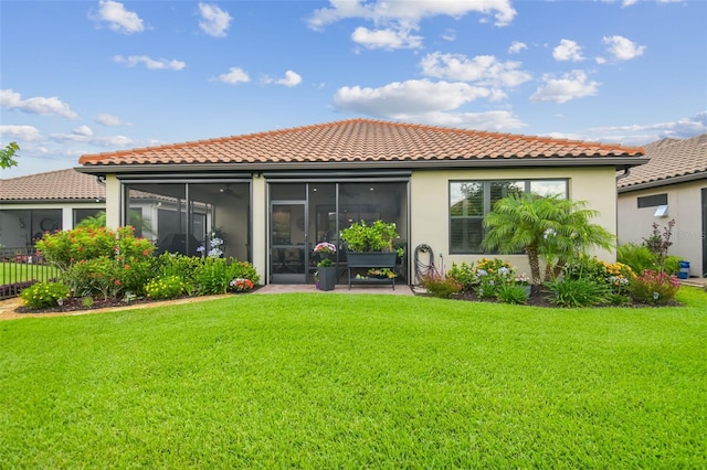 back of house with a sunroom, a tiled roof, stucco siding, and a lawn