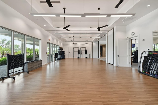 workout area featuring a high ceiling, a ceiling fan, light wood-style flooring, and baseboards