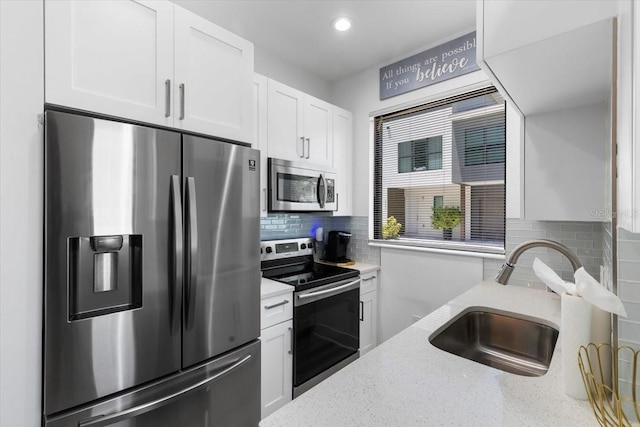 8723 Palm Ranches Pl, Tampa, FL 33614 - kitchen featuring stainless steel appliances, a sink, white cabinetry, light stone counters, and tasteful backsplash