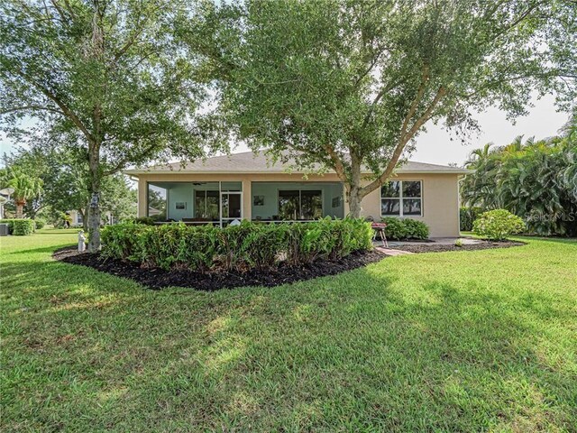 back of property with a lawn and stucco siding