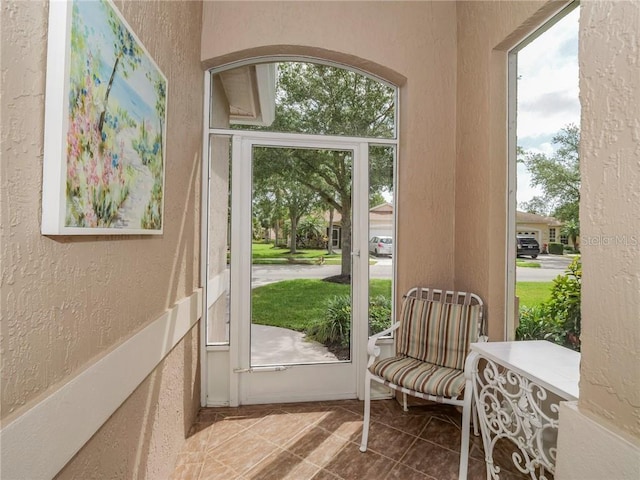 doorway with tile patterned flooring and a textured wall