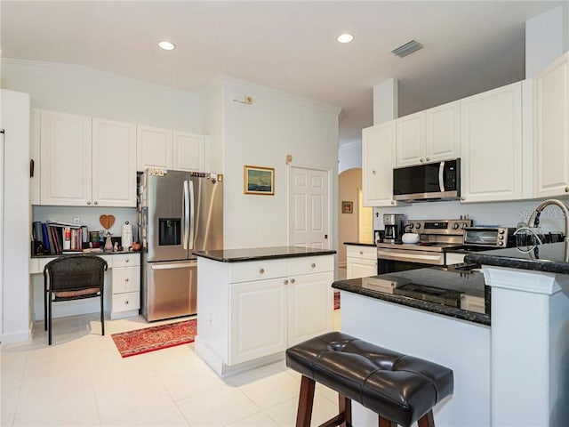 kitchen featuring stainless steel appliances, white cabinets, visible vents, and a center island