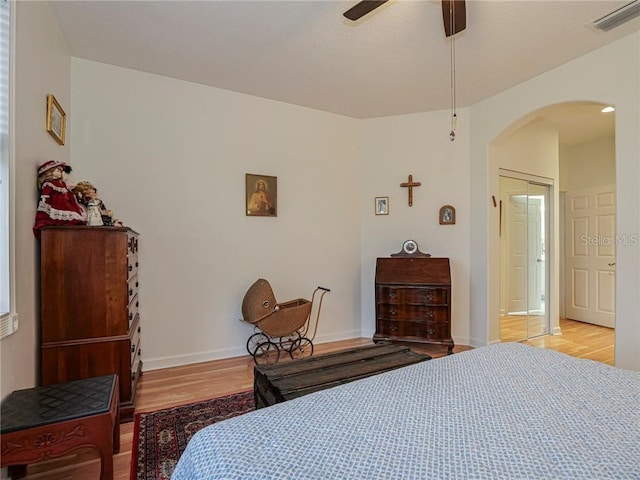 bedroom featuring wood finished floors, visible vents, baseboards, ceiling fan, and arched walkways