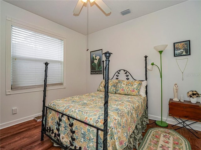 bedroom featuring baseboards, ceiling fan, visible vents, and wood finished floors