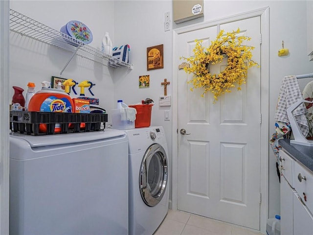 laundry area with cabinet space, light tile patterned floors, and washer and dryer