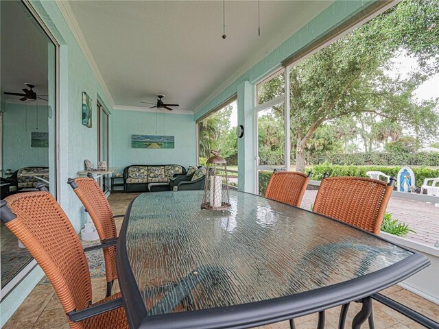 sunroom with ornamental molding, outdoor dining area, and a ceiling fan
