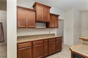kitchen featuring light countertops, open shelves, and brown cabinets