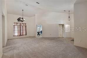carpeted spare room featuring a chandelier and lofted ceiling