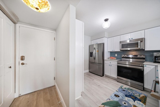 868 Bayway Blvd Unit 206, Clearwater Beach, FL 33767 - kitchen featuring stainless steel appliances, light countertops, white cabinetry, and light wood-type flooring