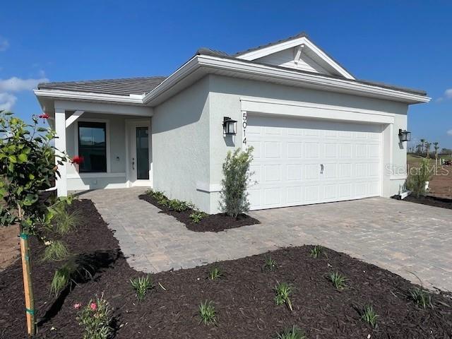 view of home's exterior with stucco siding, an attached garage, and decorative driveway