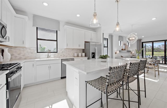 kitchen featuring appliances with stainless steel finishes, a sink, a kitchen island, a kitchen bar, and decorative backsplash
