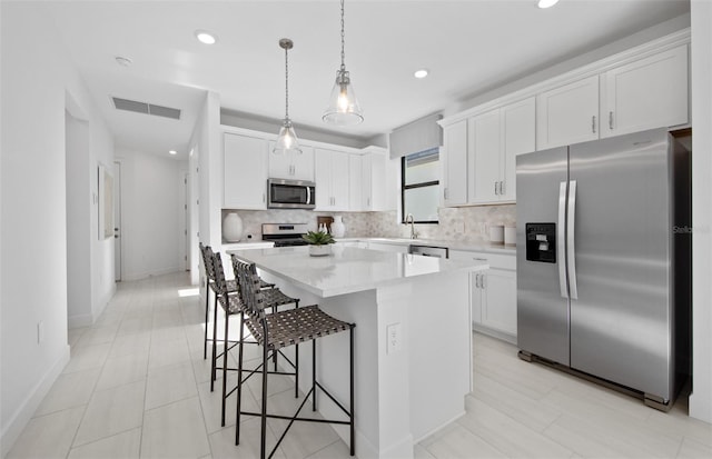 kitchen with appliances with stainless steel finishes, tasteful backsplash, a center island, a breakfast bar, and recessed lighting