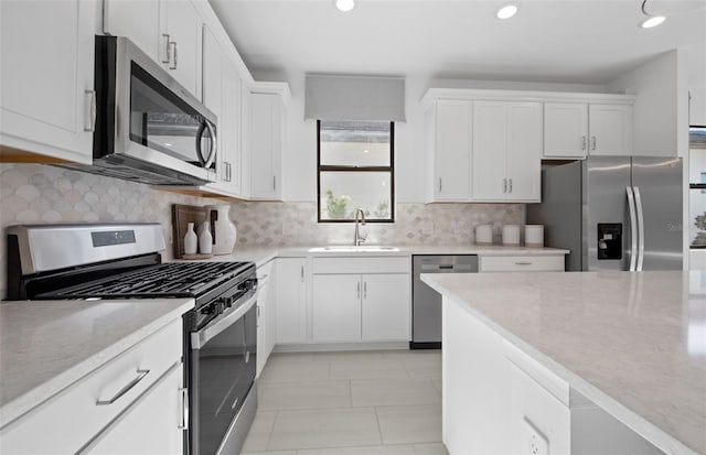 kitchen featuring stainless steel appliances, a sink, white cabinetry, and recessed lighting