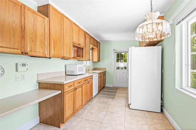 kitchen with light countertops, a wealth of natural light, a sink, and white appliances