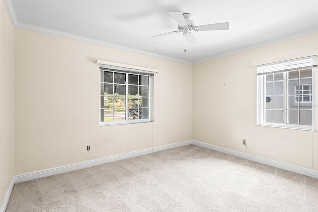 carpeted empty room with ornamental molding, baseboards, and a ceiling fan